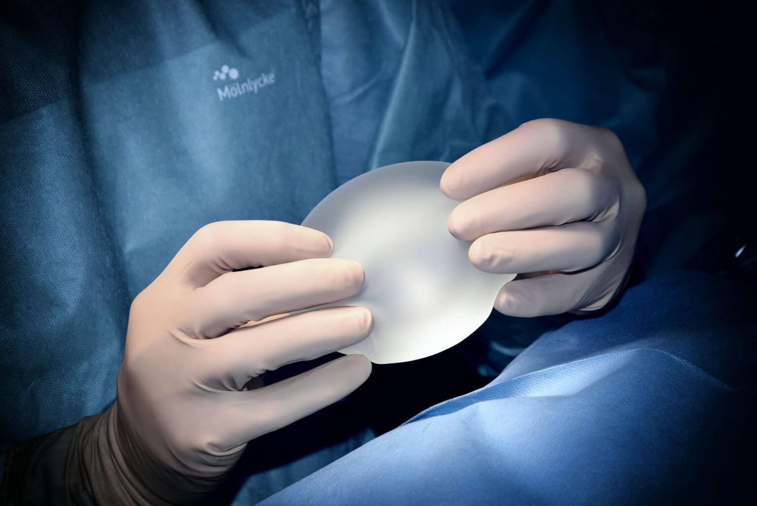 surgeon holding silicone breast implant for augmentation boob job
